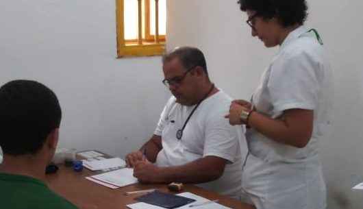 Médico e enfermeira em sala realizam consulta a um jovem rapaz